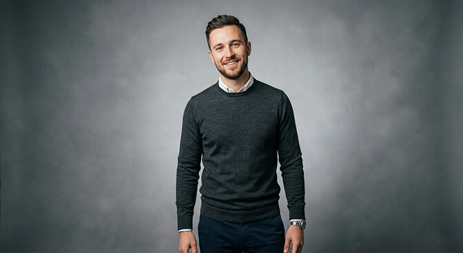 Business casual headshot style with fitted sweater or shirt clean background and relaxed professional expression