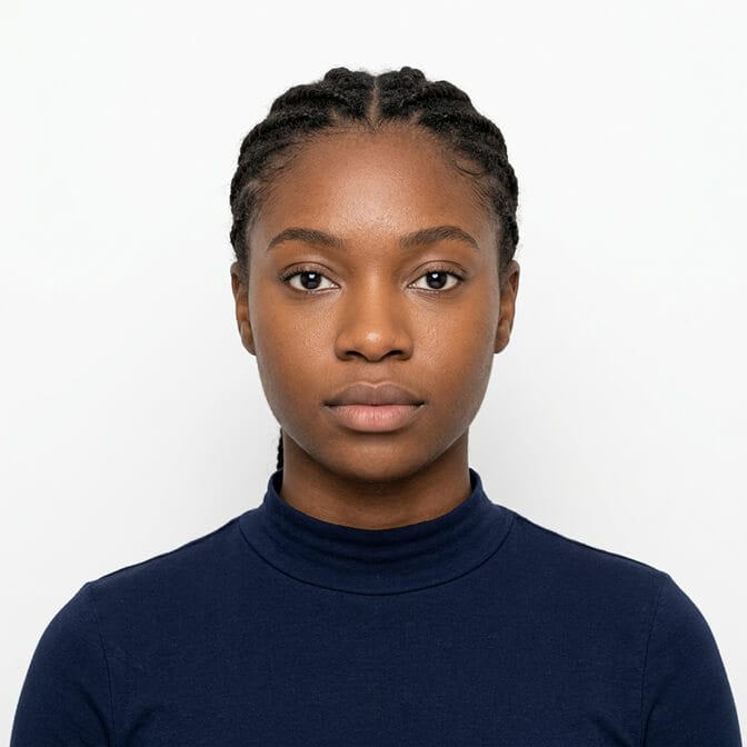 Navy crew-neck passport photo example: woman photographed straight on against a plain white background with a neutral expression, the safest colour to wear for a passport photo