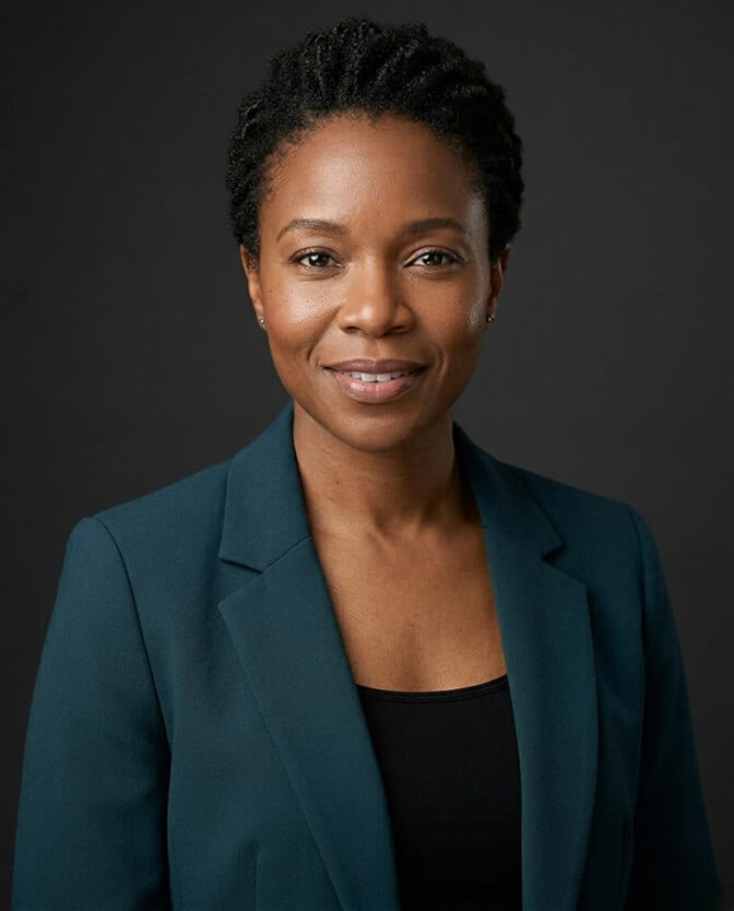 Professional headshot of a woman in a deep teal green top against a neutral background showing how the camera frames only from the chest up so the neckline shoulders and color near the face do all the work