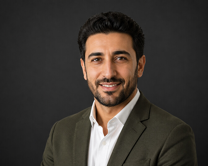 AI headshot of a smiling man with a trimmed beard in an olive blazer over a white shirt, photographed against a dark charcoal backdrop with soft key lighting.