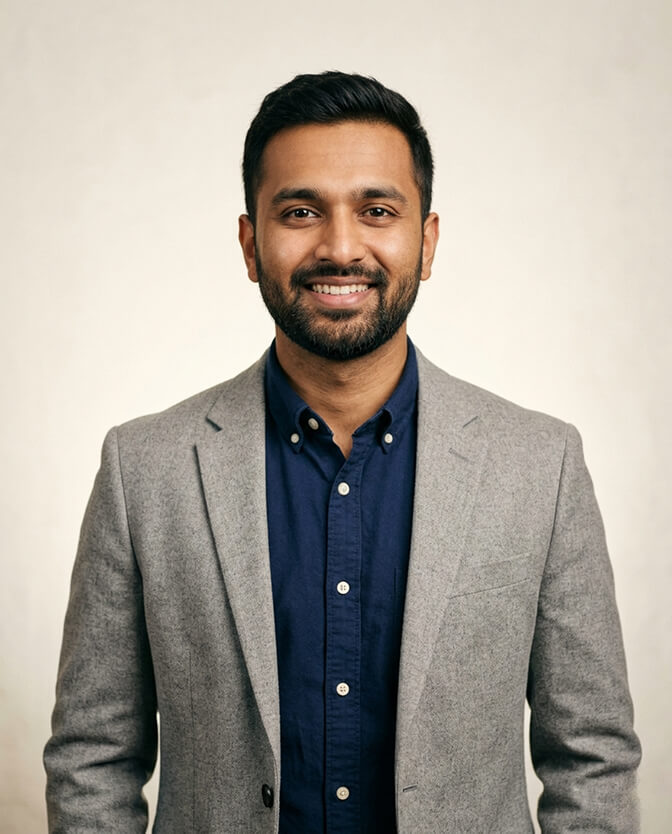 Professional AI headshot of a man in a gray blazer and navy shirt against a soft neutral background with a relaxed genuine smile showing how the right tool produces the authentic version of you the camera kept hiding