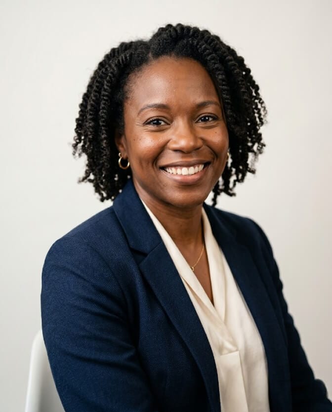 Woman in a navy blazer with a warm, genuine smile showing an office headshot that looks both approachable and confident