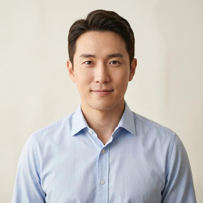 Professional headshot of a man in a light blue shirt with a warm friendly smile against a clean background projecting calm warmth and trustworthiness