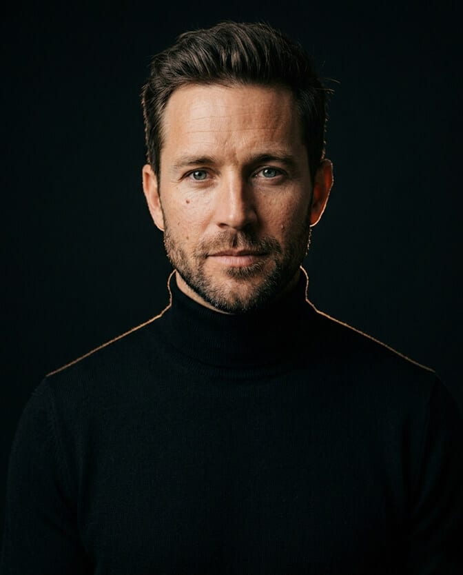Professional headshot of a man in a fitted dark turtleneck against a darker background showing the clean confident modern minimalist look